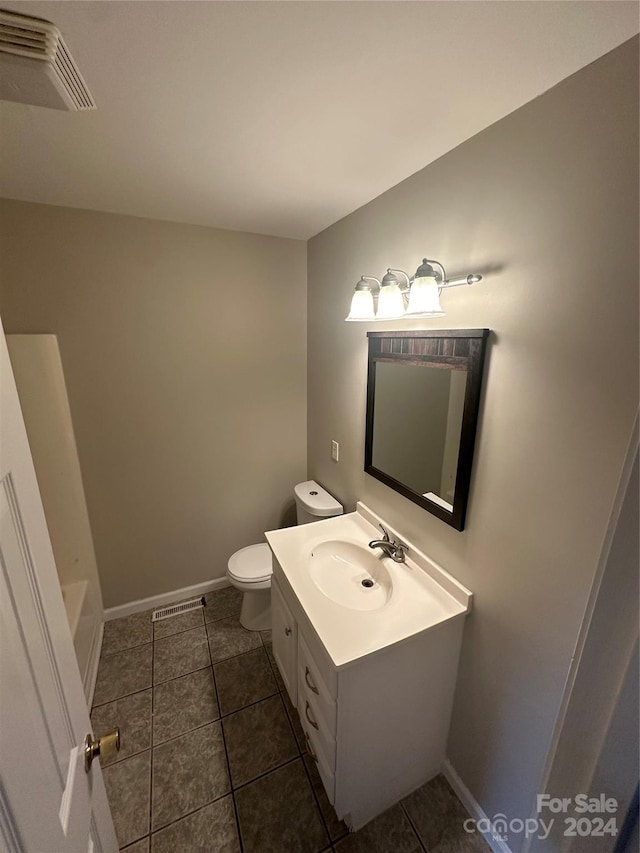 bathroom featuring tile patterned floors, vanity, toilet, and a bathing tub