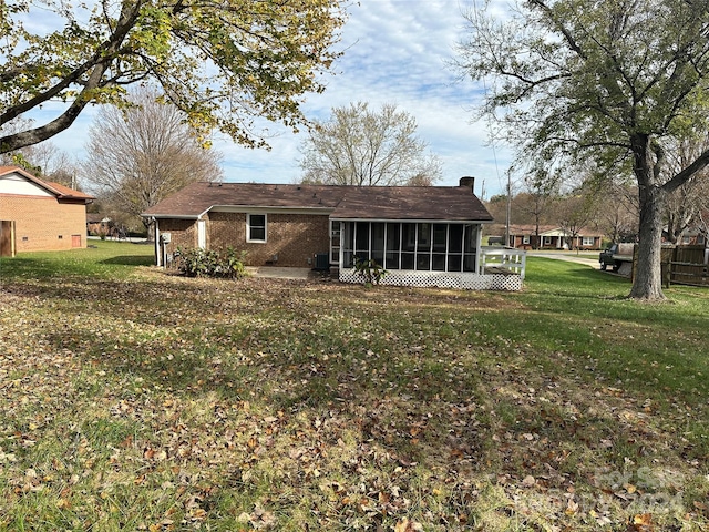 rear view of property featuring a sunroom, central AC unit, and a lawn