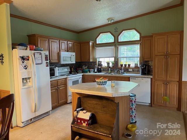 kitchen with a textured ceiling, white appliances, tile counters, backsplash, and a center island