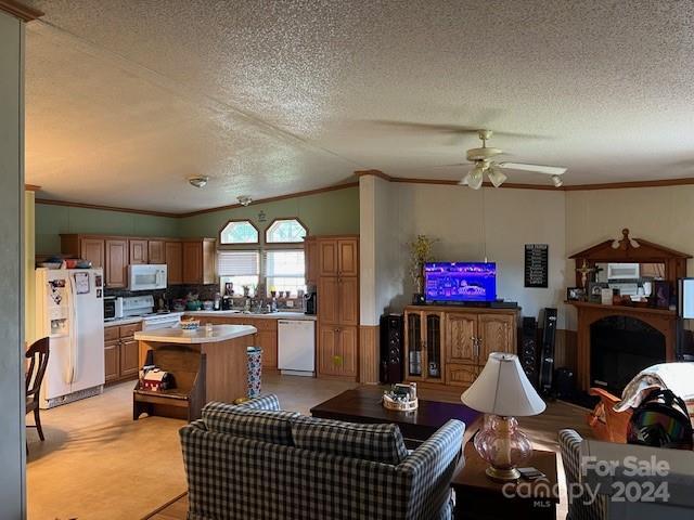 living area with a textured ceiling, a ceiling fan, and ornamental molding