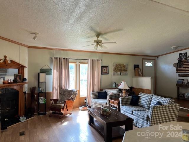 living room with ceiling fan, wood-type flooring, a textured ceiling, and crown molding