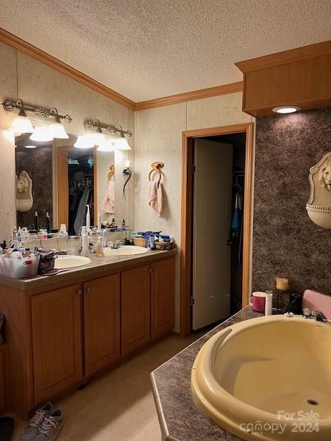 bathroom with a textured ceiling, dual vanity, and ornamental molding