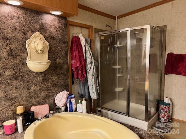 bathroom featuring crown molding, a textured ceiling, and separate shower and tub