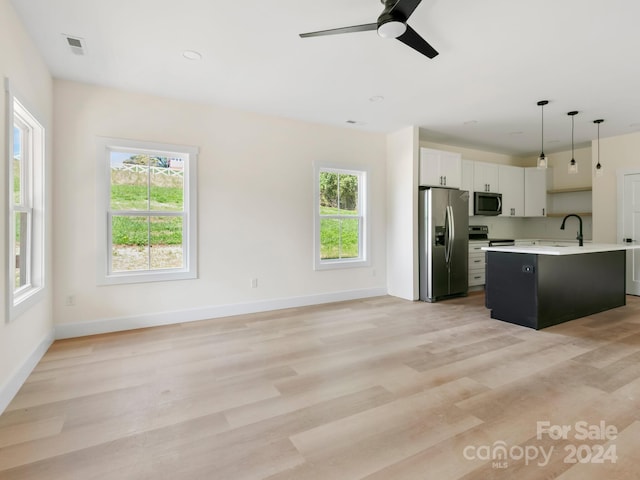 kitchen with appliances with stainless steel finishes, hanging light fixtures, a healthy amount of sunlight, and white cabinets