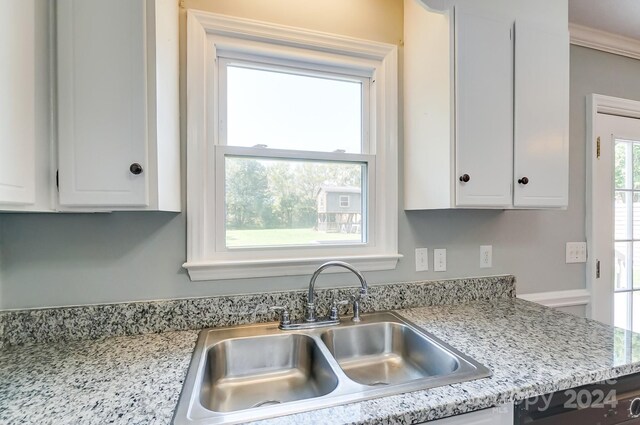 kitchen featuring white cabinetry, light stone countertops, sink, and ornamental molding