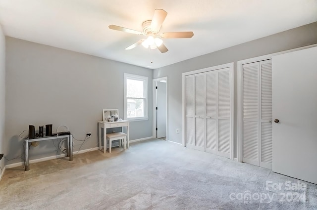 carpeted bedroom with two closets and ceiling fan