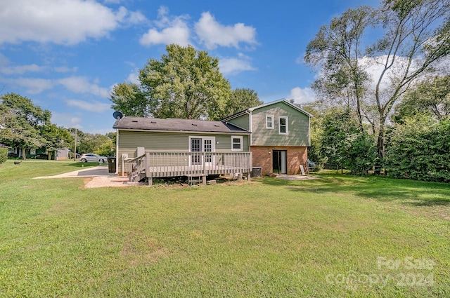 rear view of house featuring a wooden deck and a yard