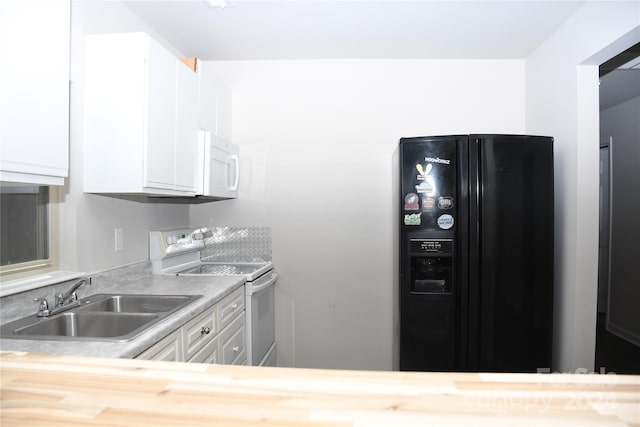 kitchen featuring black fridge, electric range oven, white cabinets, and sink