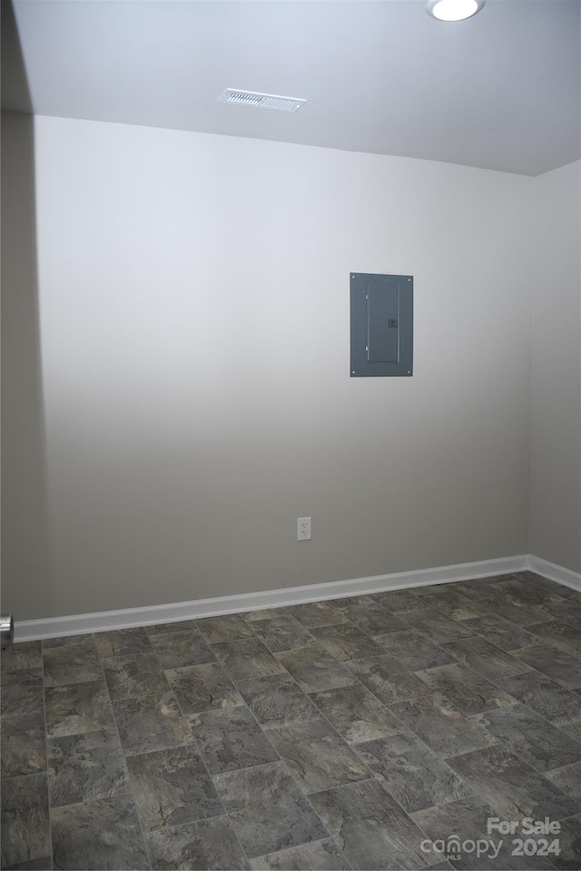 empty room with dark tile patterned floors and electric panel