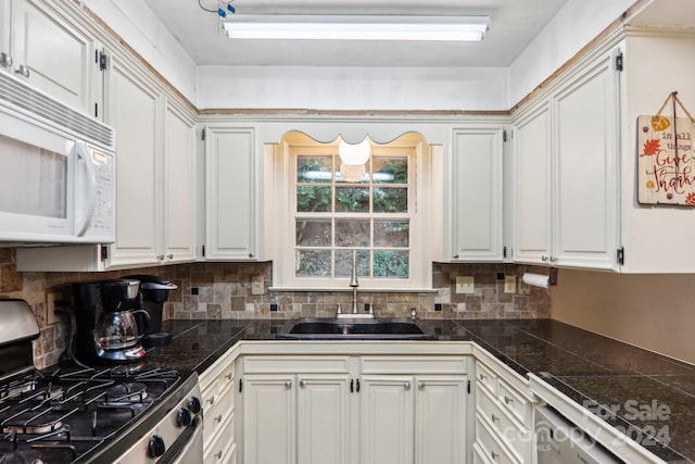 kitchen featuring stainless steel range with gas stovetop, sink, decorative backsplash, and white cabinetry