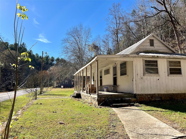 view of side of property with covered porch and a yard