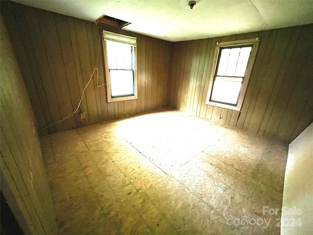 unfurnished room featuring wooden walls