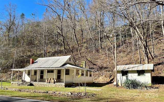 view of side of property with a lawn, covered porch, and a shed