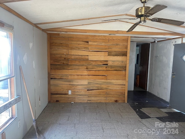 spare room with lofted ceiling, wood walls, and ceiling fan