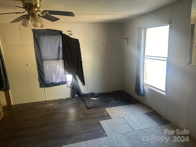 empty room with dark wood-type flooring, a textured ceiling, and ceiling fan