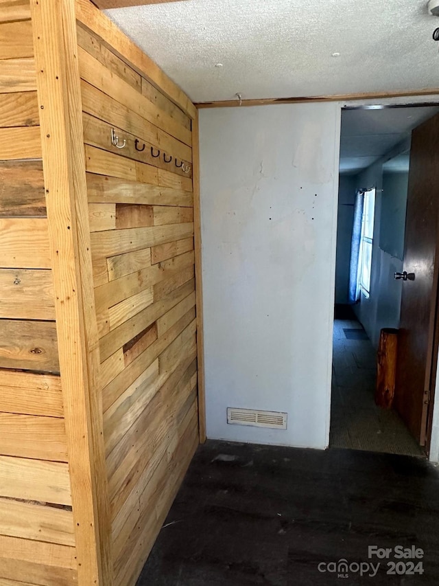 interior space with wood walls and a textured ceiling