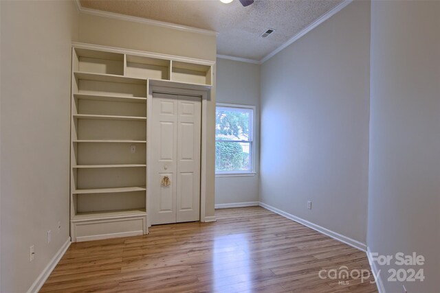 unfurnished bedroom with light hardwood / wood-style flooring, crown molding, a textured ceiling, and a closet