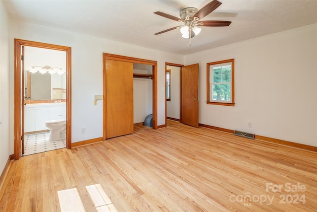 unfurnished bedroom featuring a closet, ensuite bathroom, light tile patterned floors, and ceiling fan