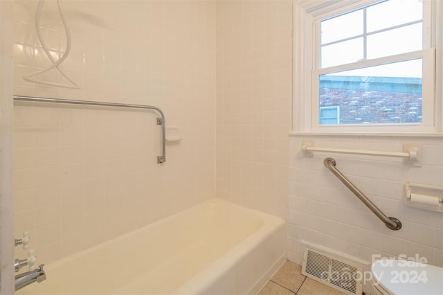 bathroom with tiled shower / bath combo, toilet, tile patterned floors, and plenty of natural light