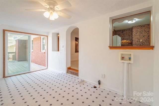 carpeted spare room with a textured ceiling, brick wall, and ceiling fan