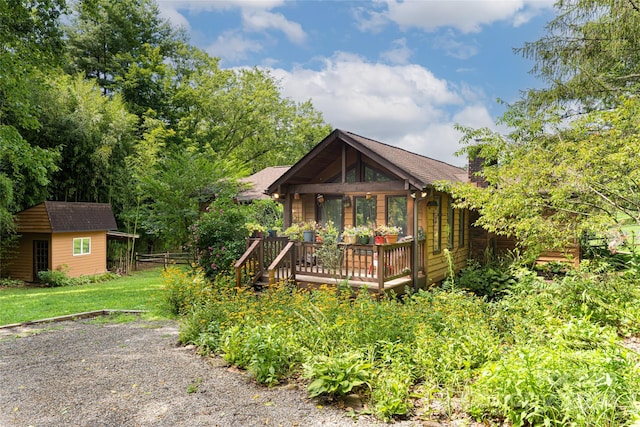 exterior space featuring a wooden deck, a storage unit, and a front lawn