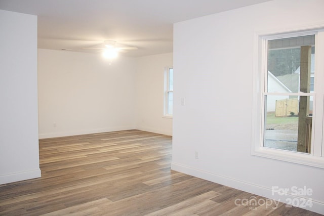 empty room with baseboards, wood finished floors, and ceiling fan