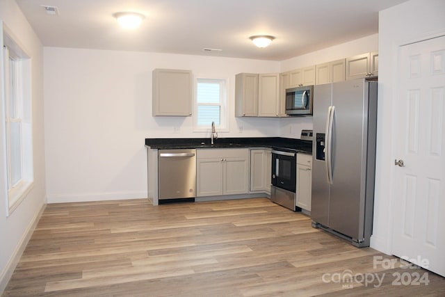 kitchen featuring sink, appliances with stainless steel finishes, light wood-type flooring, and cream cabinetry