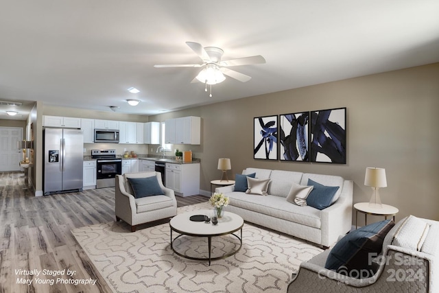 living room with sink, light hardwood / wood-style flooring, and ceiling fan