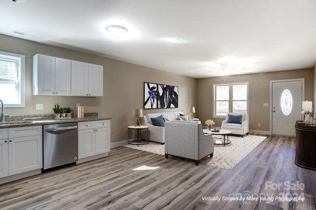 kitchen featuring light hardwood / wood-style flooring, white cabinets, light stone counters, dishwasher, and ceiling fan