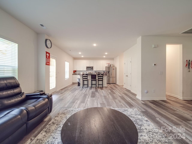 living area featuring recessed lighting, visible vents, baseboards, and light wood finished floors