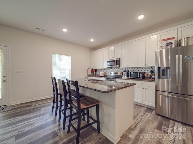 kitchen featuring wood finished floors, visible vents, a sink, stainless steel appliances, and backsplash