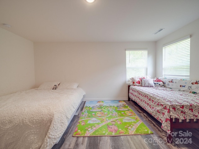 bedroom with visible vents, baseboards, and wood finished floors