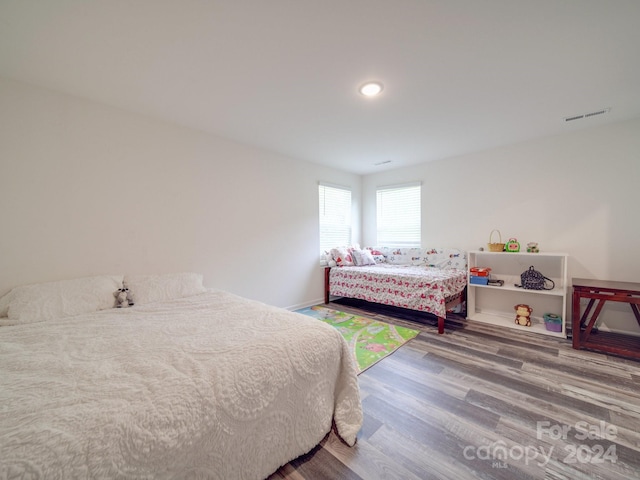 bedroom with visible vents, baseboards, and wood finished floors