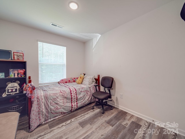 bedroom with wood finished floors, visible vents, and baseboards