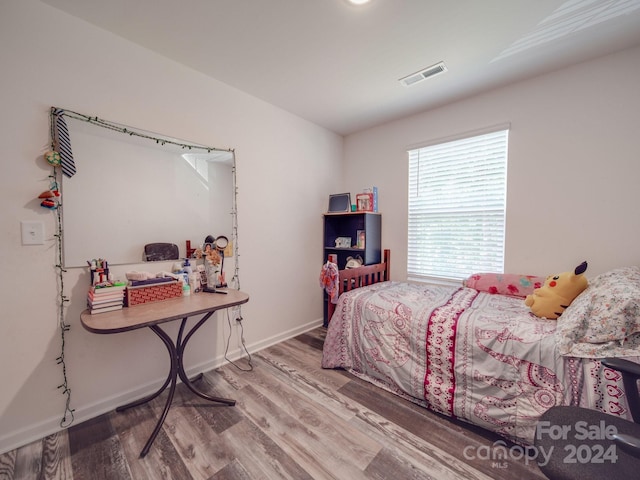 bedroom featuring wood finished floors, visible vents, and baseboards