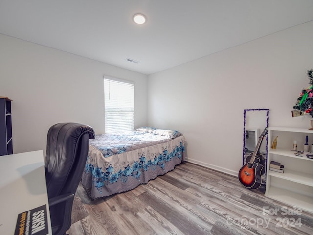 bedroom featuring visible vents, baseboards, and wood finished floors