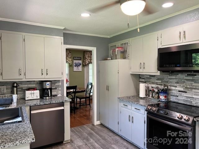 kitchen with appliances with stainless steel finishes, tasteful backsplash, hardwood / wood-style flooring, white cabinetry, and ceiling fan