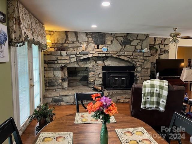 interior space with a stone fireplace, ceiling fan, and wood-type flooring