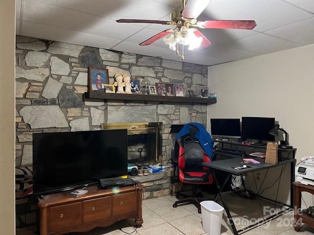 tiled office with a stone fireplace, ceiling fan, and a drop ceiling