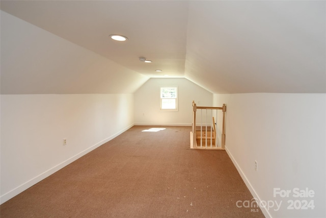 bonus room with lofted ceiling and carpet flooring