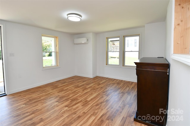 unfurnished room featuring hardwood / wood-style flooring and a wall mounted air conditioner