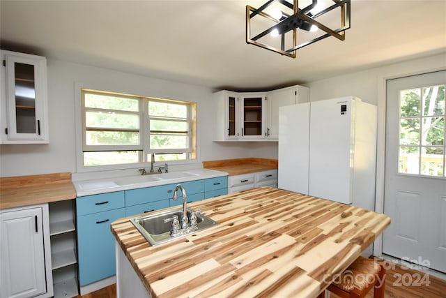 kitchen with white cabinetry, sink, butcher block countertops, and white refrigerator