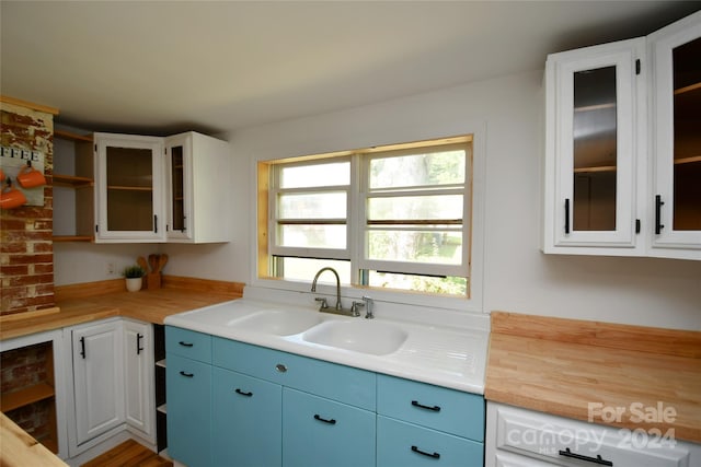 kitchen with sink, white cabinets, and blue cabinetry