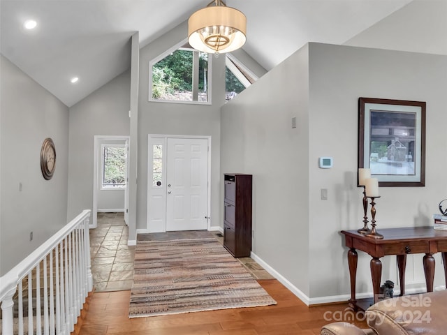 foyer entrance with hardwood / wood-style floors, high vaulted ceiling, and a wealth of natural light