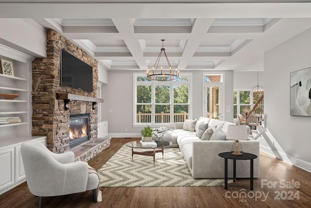 living room with beam ceiling, dark hardwood / wood-style flooring, a stone fireplace, and a notable chandelier