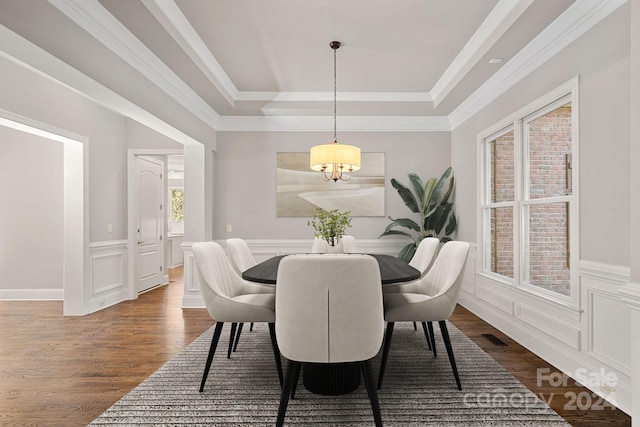 dining area with dark hardwood / wood-style flooring, a raised ceiling, and ornamental molding