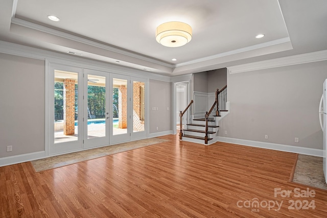 spare room with hardwood / wood-style floors, a raised ceiling, ornamental molding, and french doors