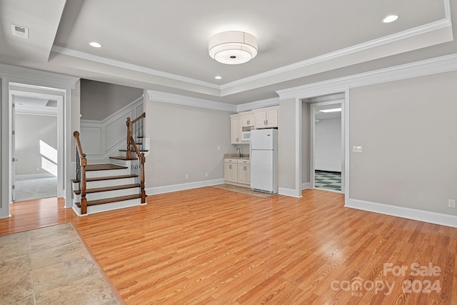 living room with light hardwood / wood-style floors, crown molding, and a tray ceiling