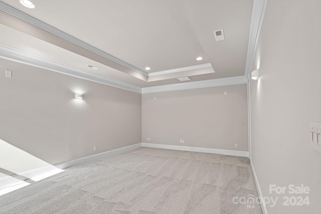 empty room featuring ornamental molding, light carpet, and a tray ceiling