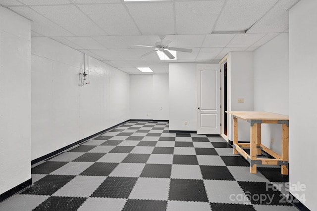 basement with a paneled ceiling and ceiling fan